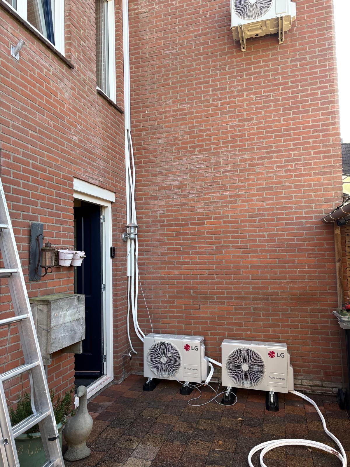Twee geïnstalleerde LG airconditioning buitenunits tegen de gevel van een woning